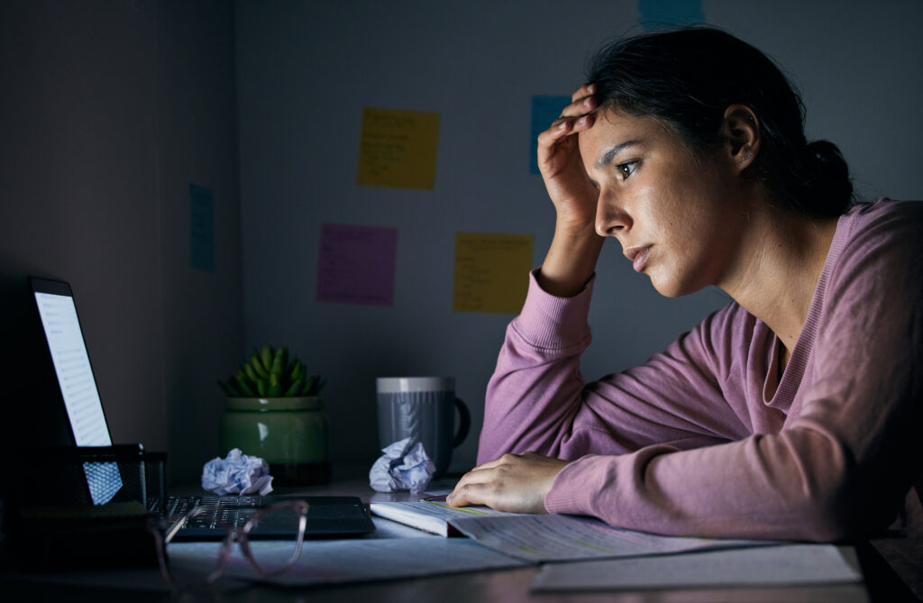 Student working on last minute scholarships at night on a laptop